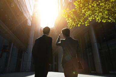 Two businessmen looking up into the sun.
