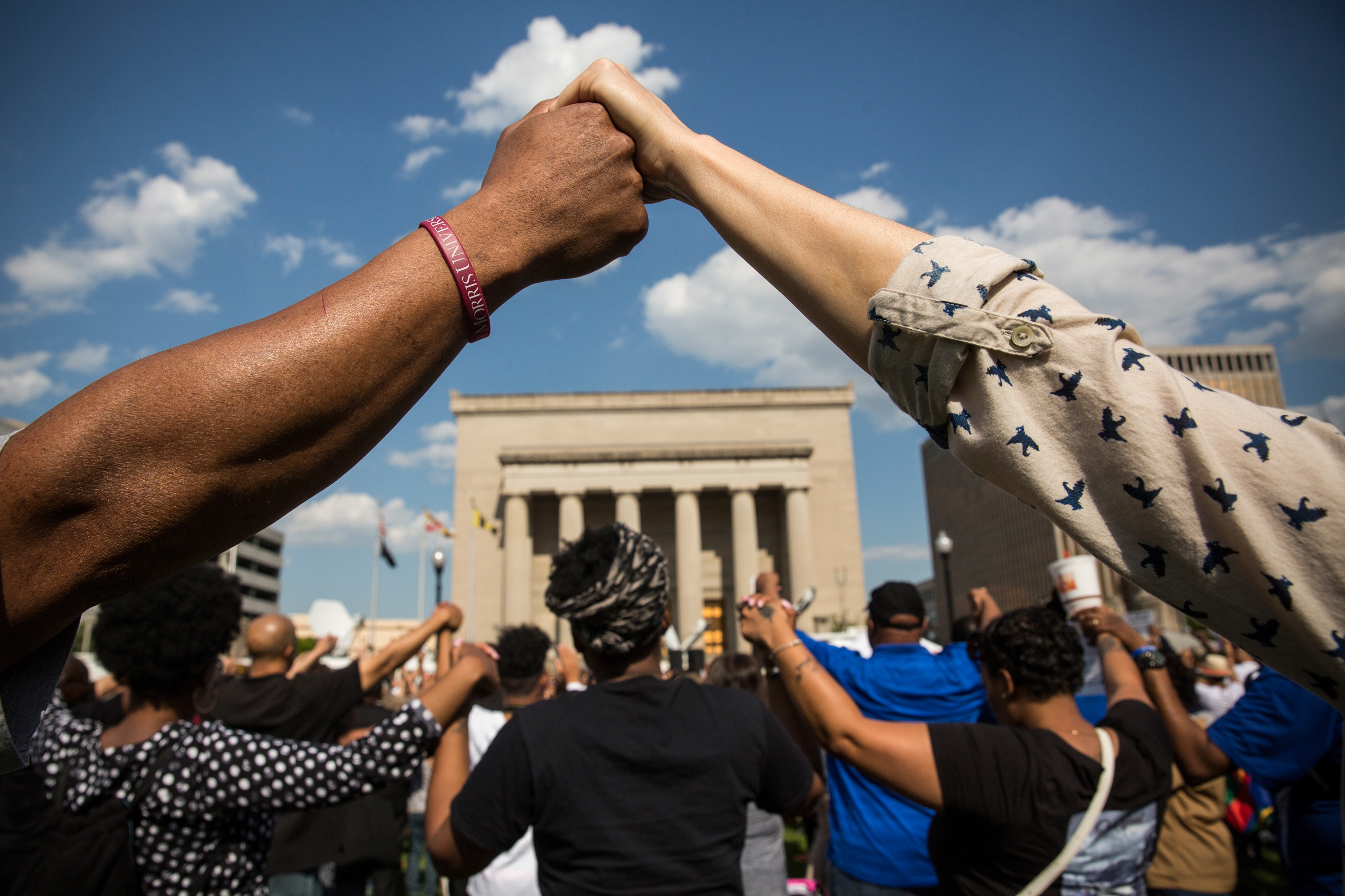 BALTIMORE, MD - MAY 03:  People hold hands during a rally lead by faith leaders in front of city hall calling for justice in response to the death of Freddie Gray on May 3, 2015 in Baltimore, Maryland. Gray later died in custody; the Maryland state attorney announced on Friday that charges would be brought against the six police officers who arrested Gray.  (Photo by Andrew Burton/Getty Images)