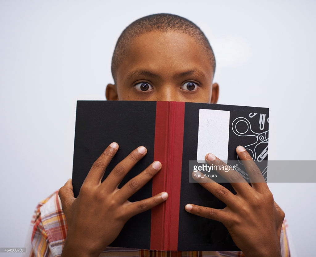 A young boy doing prepared reading at the front of the class