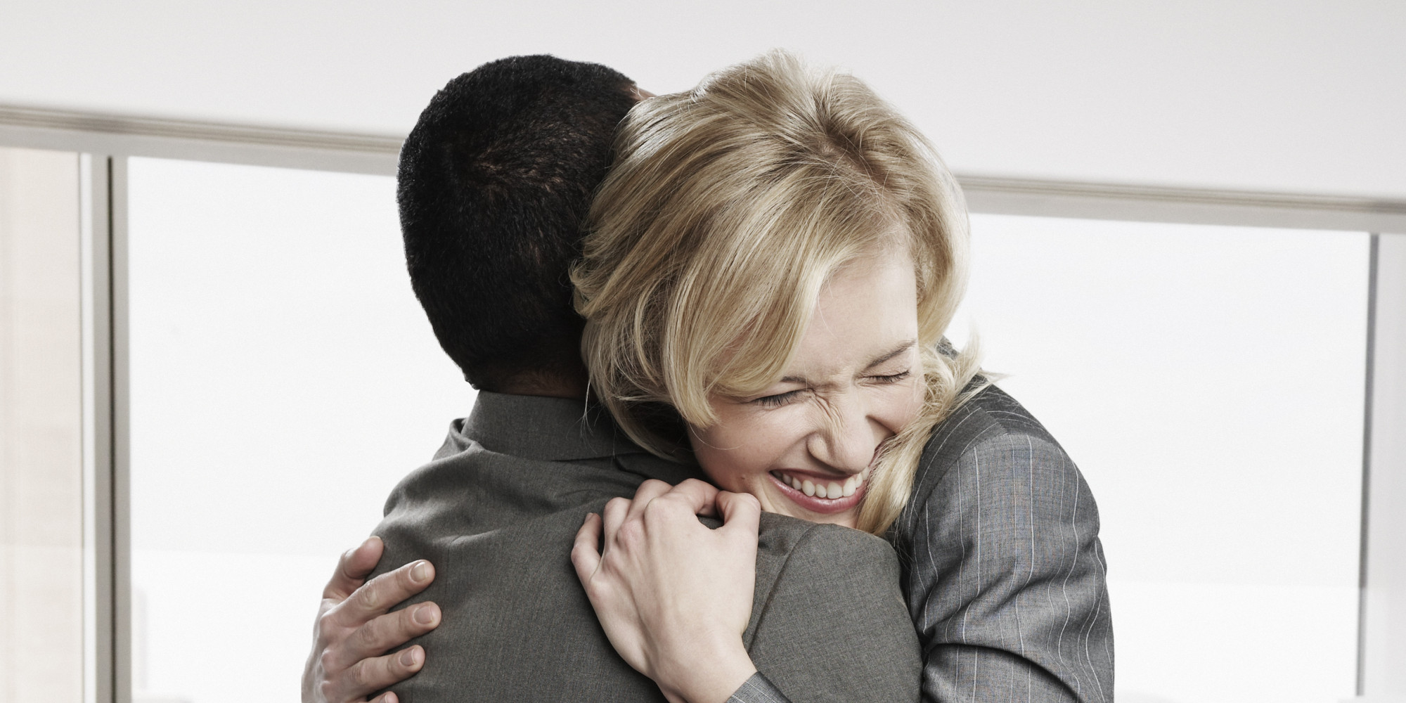 Two business people hugging in office